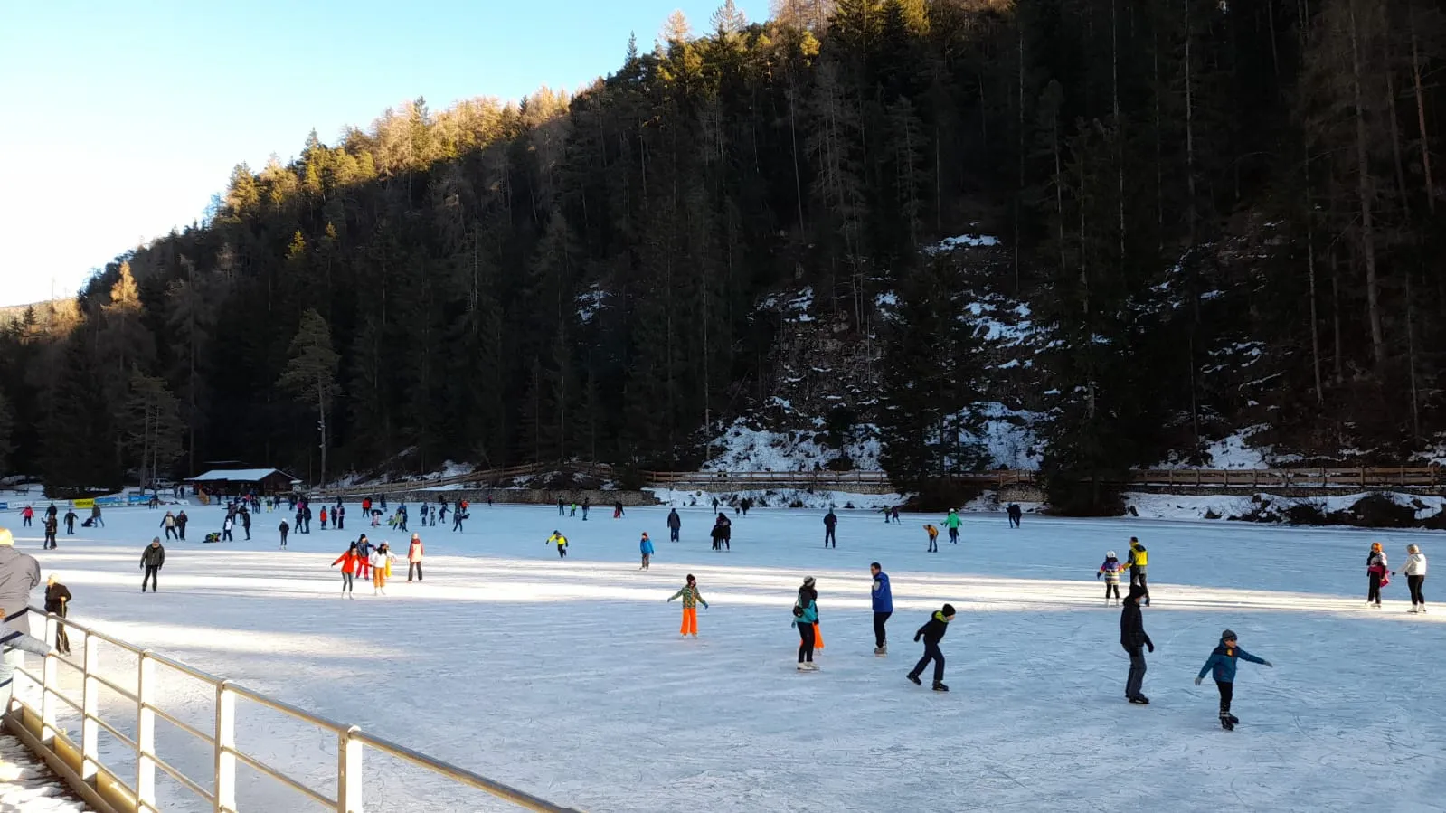 Pattinatori sul Lago Smeraldo ghiacciato accanto al Palasmeraldo, dove il gestore realizza una pista all'aperto sul ghiaccio del lago a Natale se il tempo lo permette. – Palasmeraldo (Stadio del ghiaccio)