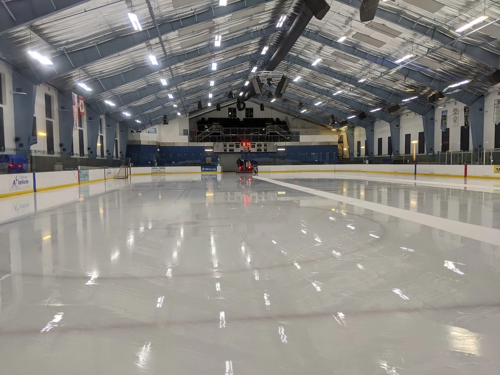 The empty sheet from the corner of the ice, under the arched roof with the far-end seating and scoreboard. — Palm Beach Ice Works
