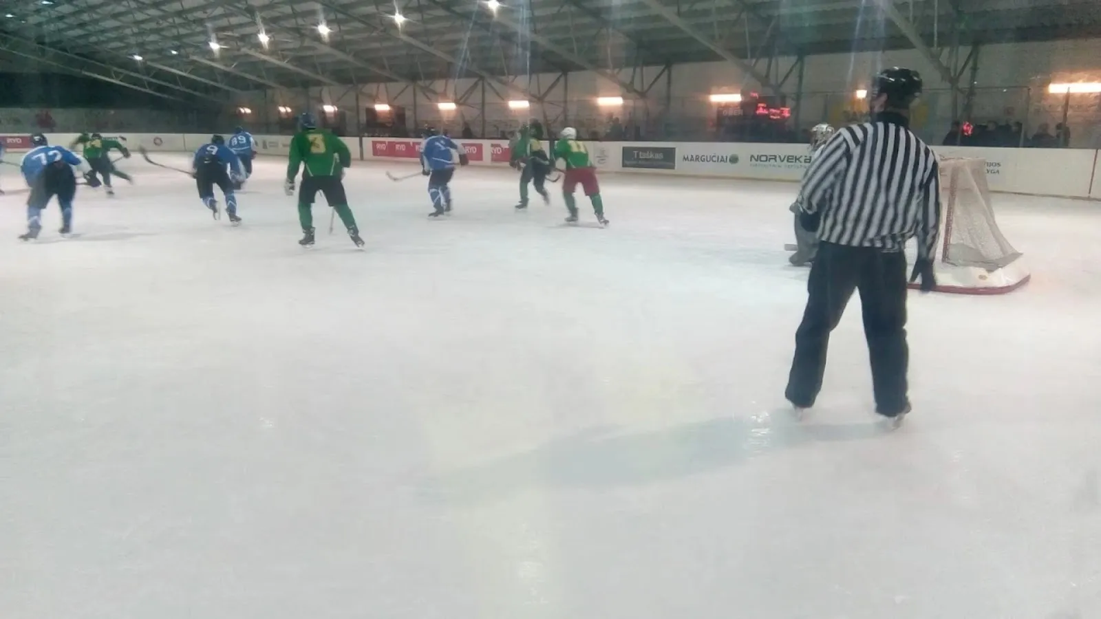 A game on the ice at Panevėžio Ledo Arena with a referee and players at the far end — Panevėžio ledo arena