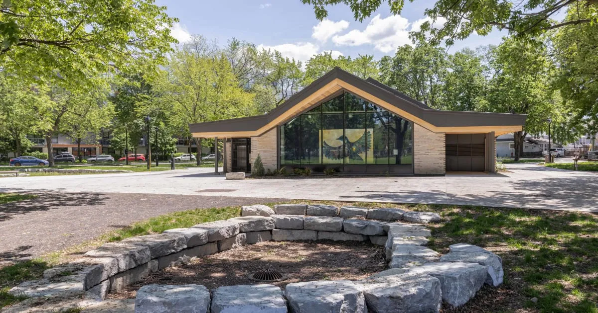 The glass-fronted field house at Parc Saint-Victor with a stone-ringed gathering circle in front (City of Montréal photo) — Parc Saint-Victor Outdoor Rinks