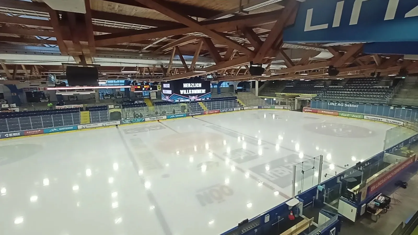 The empty indoor ice of the LINZ AG Eisarena with its boards and sponsor signs (Google Maps listing photo) — Parkbad Eishalle Linz