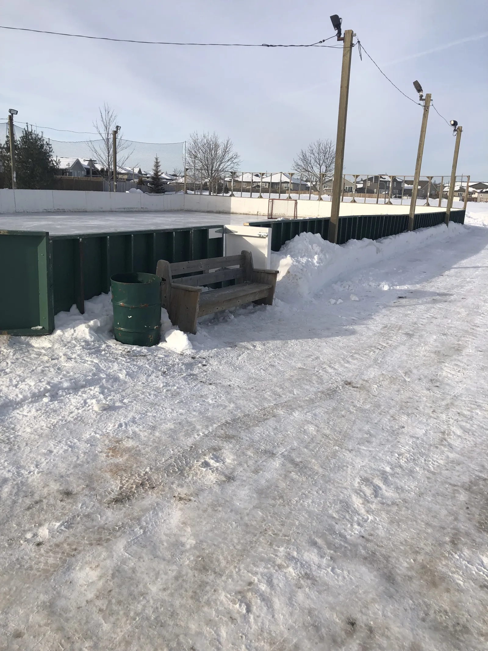 Boards, a bench and a bin along the Parkdale Park rink — Parkdale Park Outdoor Rink