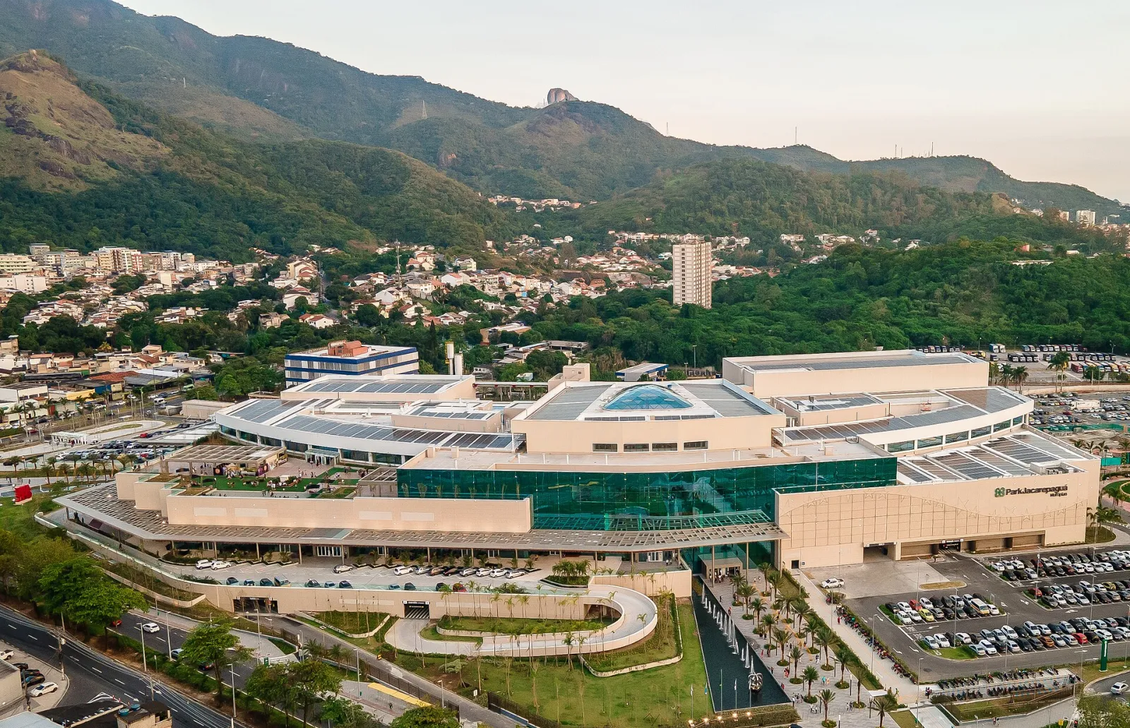 ParkJacarepaguá shopping centre seen from the air, a long low building with a glass front below green hills — ParkJacarepaguá Ice Rink