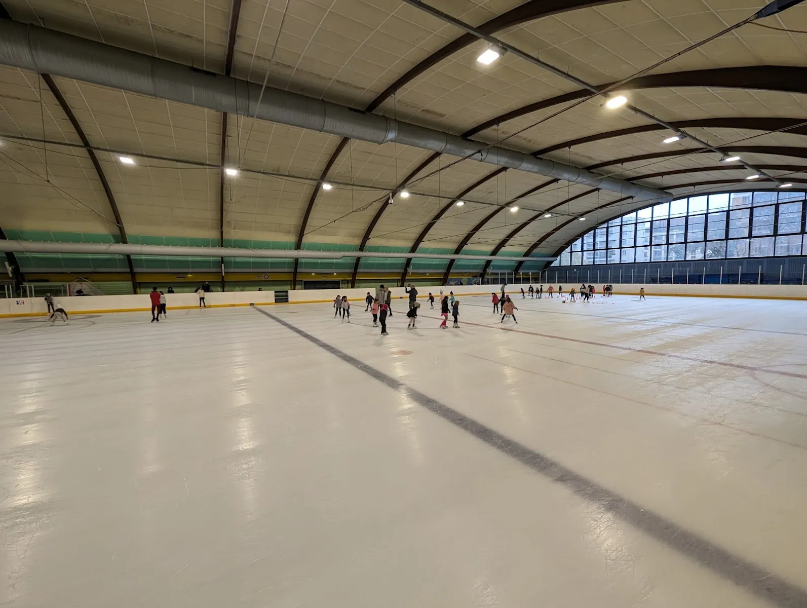 La longue halle voûtée de la patinoire Baraban avec quelques patineurs de l’autre côté de la glace — Patinoire Baraban