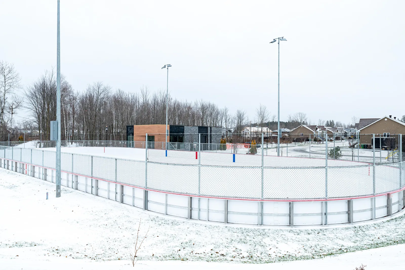 La patinoire de la Seigneurie à Drummondville sous la neige, vue de côté, avec ses bandes, ses projecteurs et le chalet à l'arrière — Patinoire de la Seigneurie