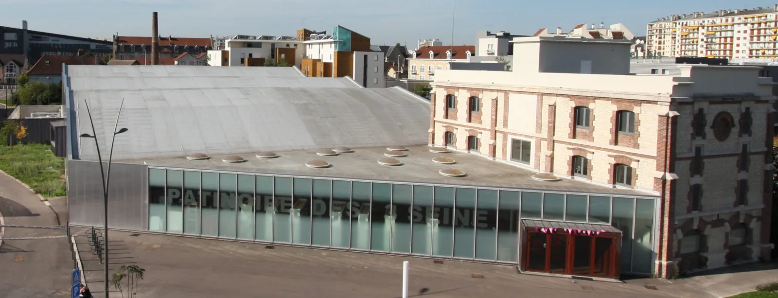 The rink building seen from above, a long glazed front with the name on it beside the older brick building of the leisure complex — Patinoire des 3 Seine