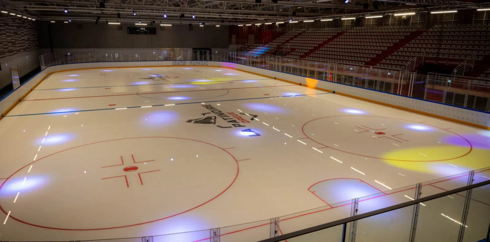 La surface de glace vide de la patinoire de Dreux, avec des gradins de chaque côté — Patinoire de Dreux