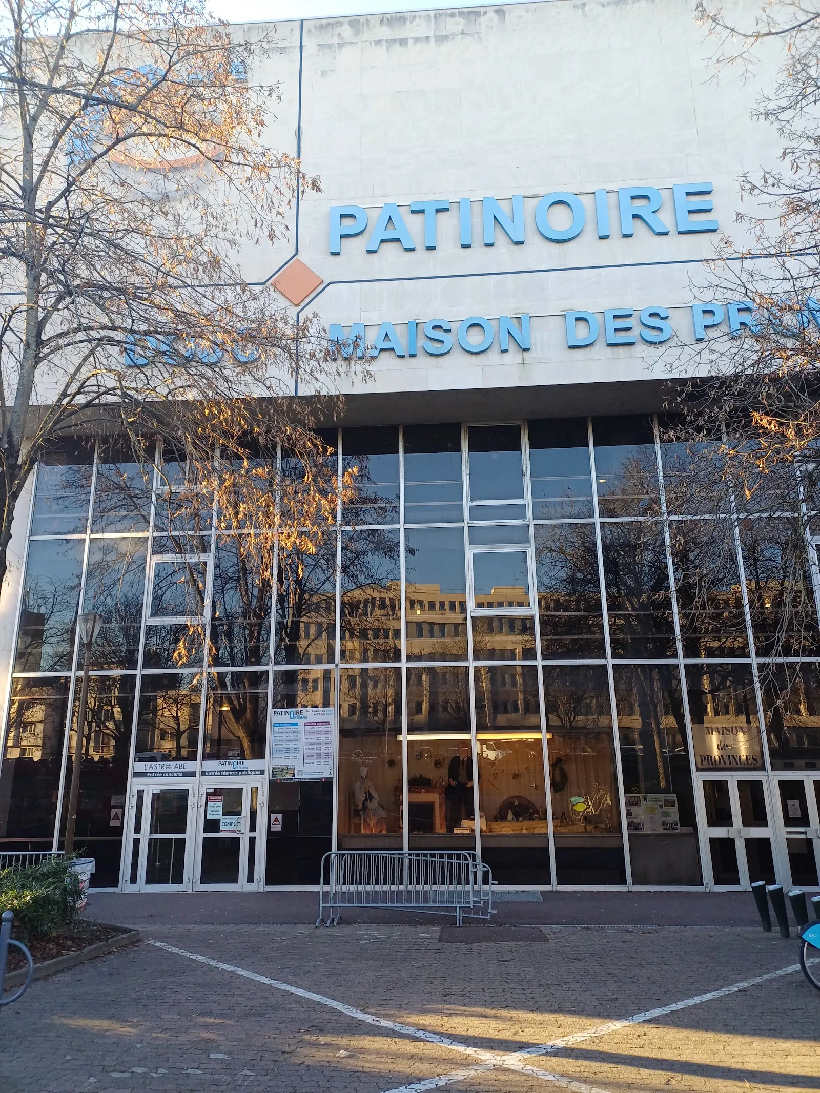 La façade vitrée de la patinoire d’Orléans sur le boulevard Jean Jaurès, avec le mot « Patinoire » au-dessus des portes et des arbres nus devant — Patinoire d'Orléans