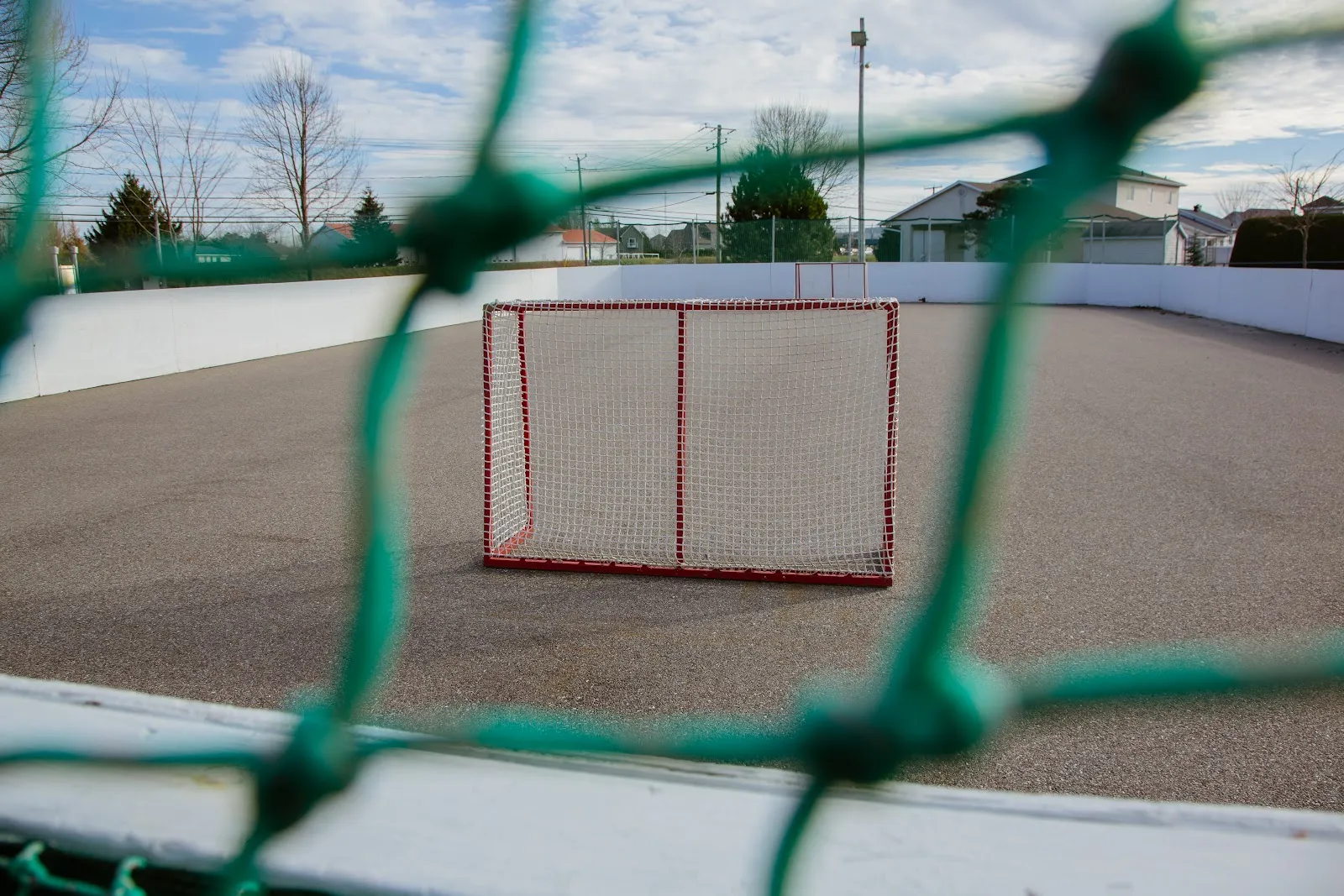 The boarded rink at Parc Catherine in the off-season, with a goal on the bare surface — Patinoire du parc Catherine