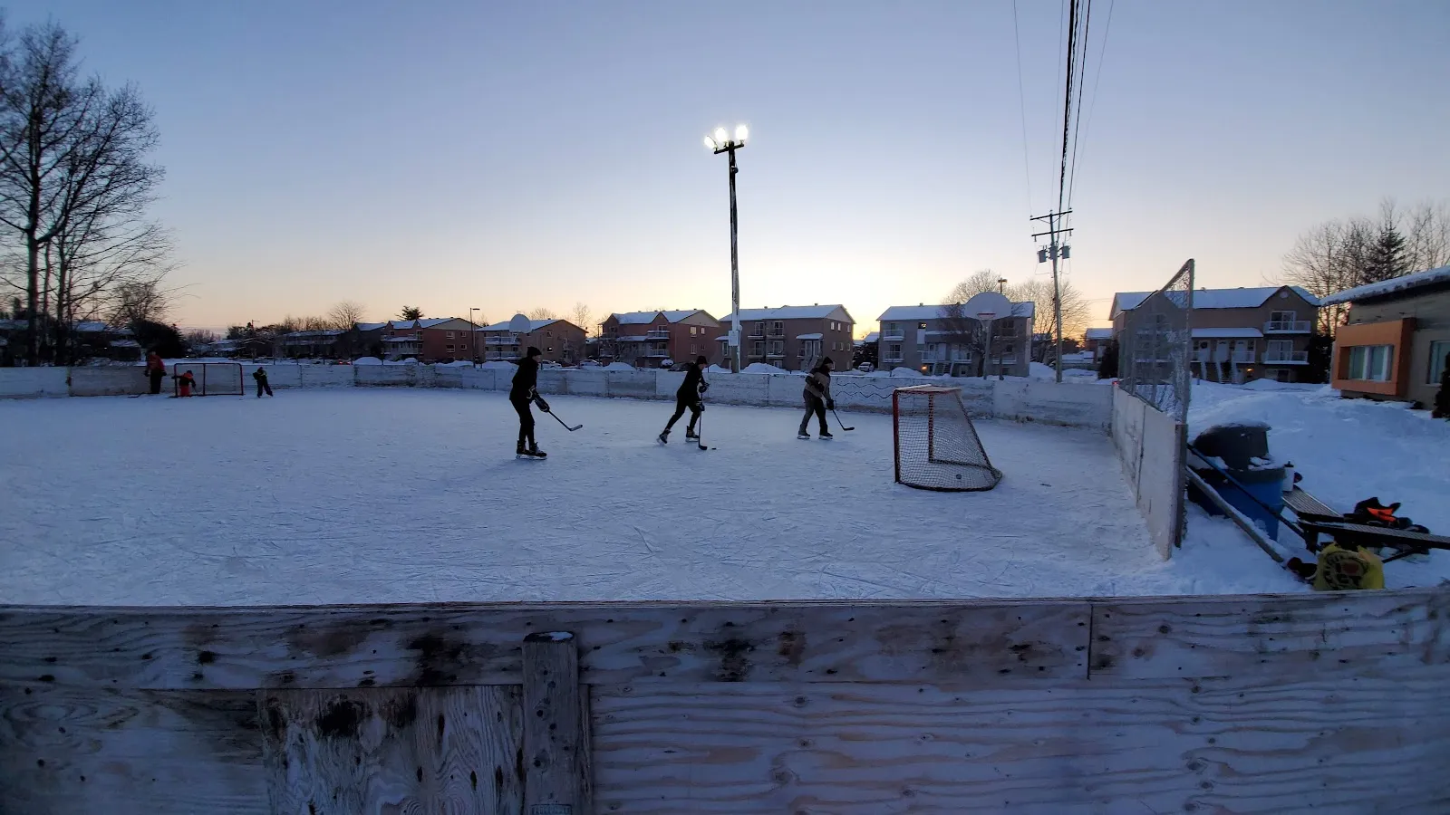The floodlit outdoor rink at Parc La Vérendrye in Gatineau at dusk, with a goal and skaters at a distance — Patinoire du parc La Vérendrye (Gatineau)