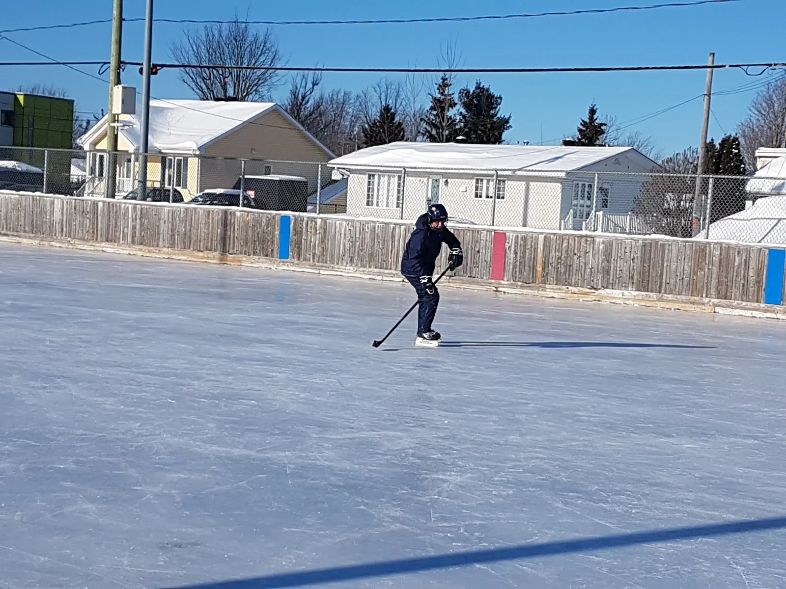 A hockey player on the boarded outdoor rink at Parc Ovila-Bernier on a sunny winter day — Patinoire du parc Ovila-Bernier (Saint-Lin–Laurentides)