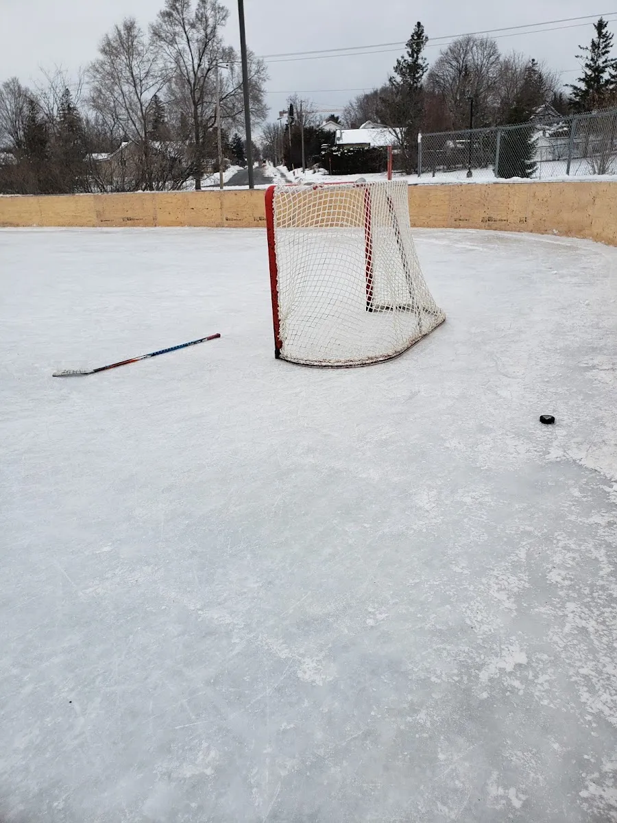The empty ice of the outdoor rink at Parc Woods in Gatineau, with a hockey net and stick on the ice and the boards behind — Patinoire du parc Woods (Gatineau)