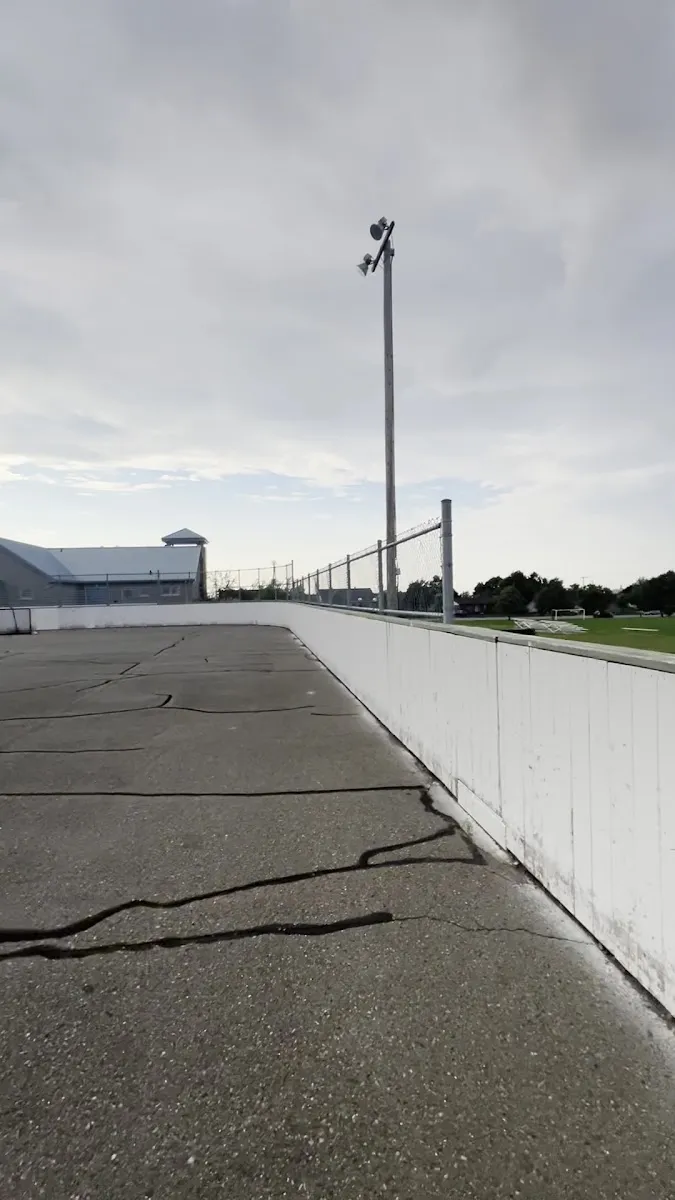 La surface vide de la patinoire extérieure avec bandes de la Terrasse Arthur-Buies en été : bandes blanches, poteaux d'éclairage et maisons à l'arrière-plan. — Patinoire extérieure de Terrasse Arthur-Buies