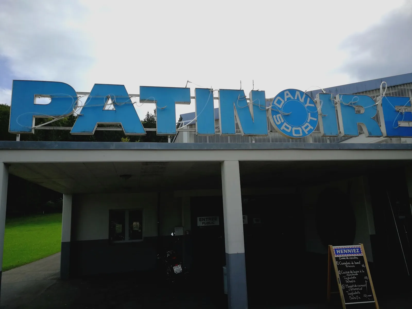 The Patinoire sign above the dark entrance canopy of the Jean Tinguely rink in Marly. — Patinoire Jean Tinguely
