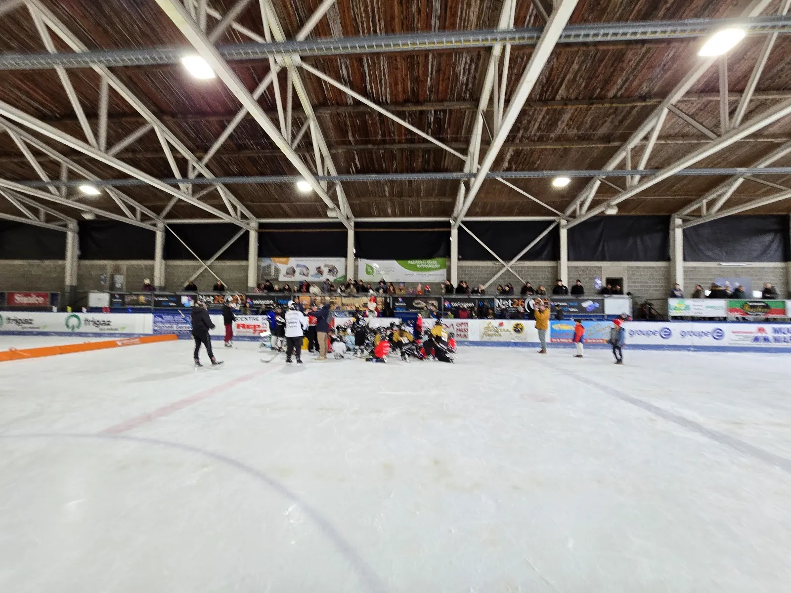 A few skaters at the far end of the covered Jean Tinguely rink in Marly under the steel roof frame. — Patinoire Jean Tinguely