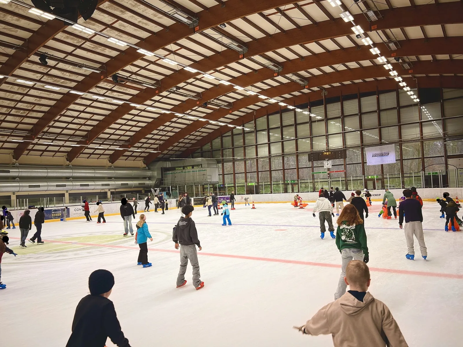 Des patineurs sur la glace dans la halle de Kockelscheuer sous son toit courbe en bois. — Patinoire Kockelscheuer
