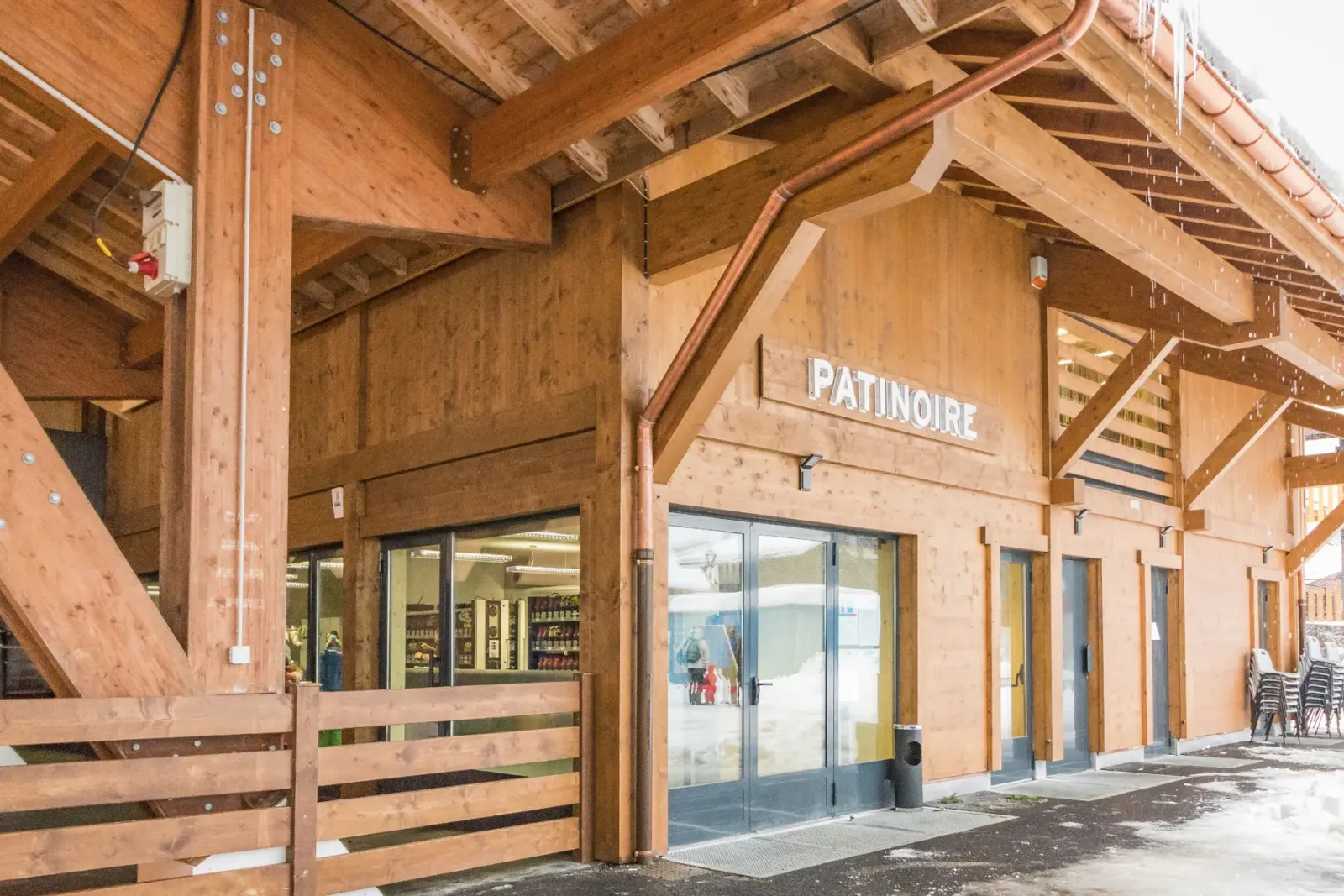 L’entrée en bois de la patinoire du Grand-Bornand, un bâtiment en bois avec l’enseigne PATINOIRE au-dessus de portes vitrées. — Patinoire du Grand-Bornand
