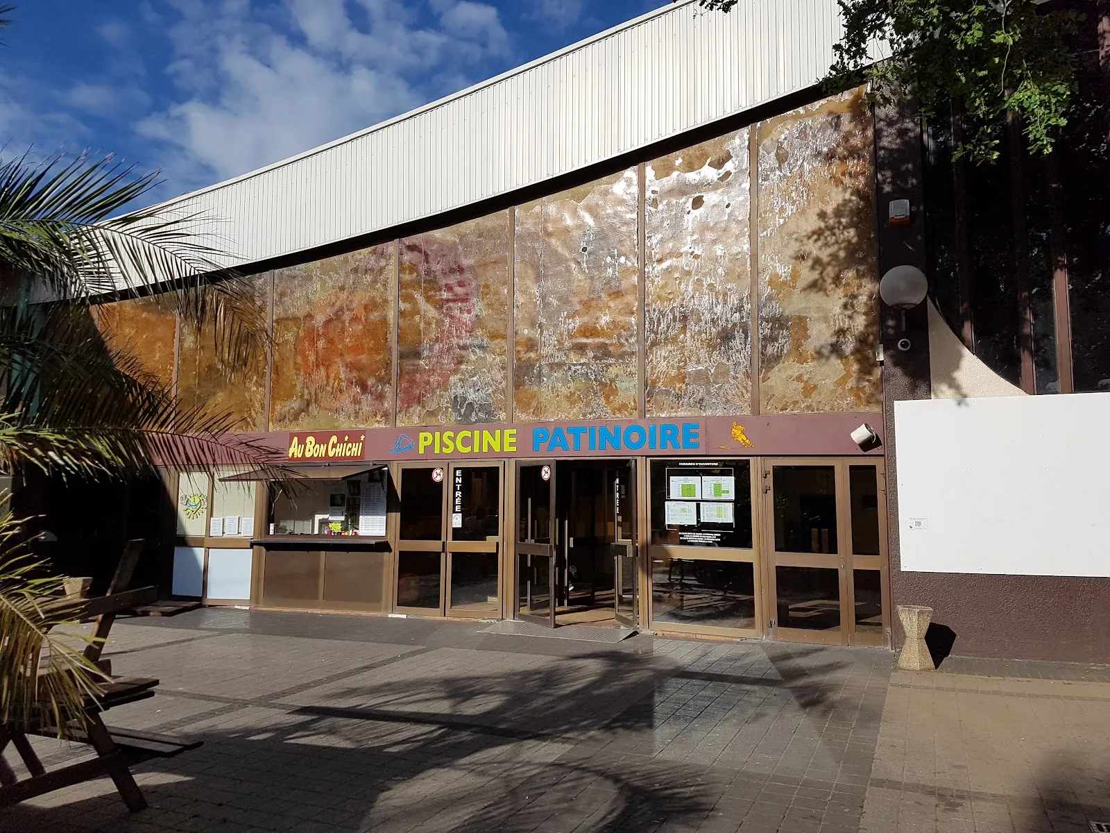 The glazed entrance of the Piscine-Patinoire at Amnéville under the curved roof of the complex, with the snack bar window beside the doors — Patinoire olympique d'Amnéville