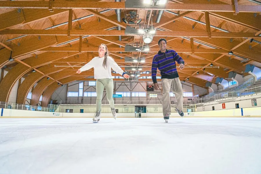 La halle voûtée en bois et la glace de la patinoire olympique de Pralognan-la-Vanoise avec deux patineurs — Patinoire Olympique de Pralognan-la-Vanoise (Le Cristal)