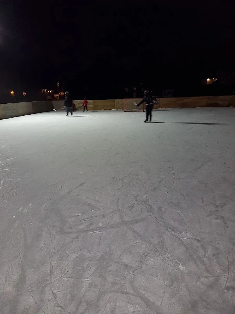 The floodlit outdoor rink at Parc Marcel-Fredette at night, with skaters in the distance on the ice — Patinoire Parc Marcel-Fredette