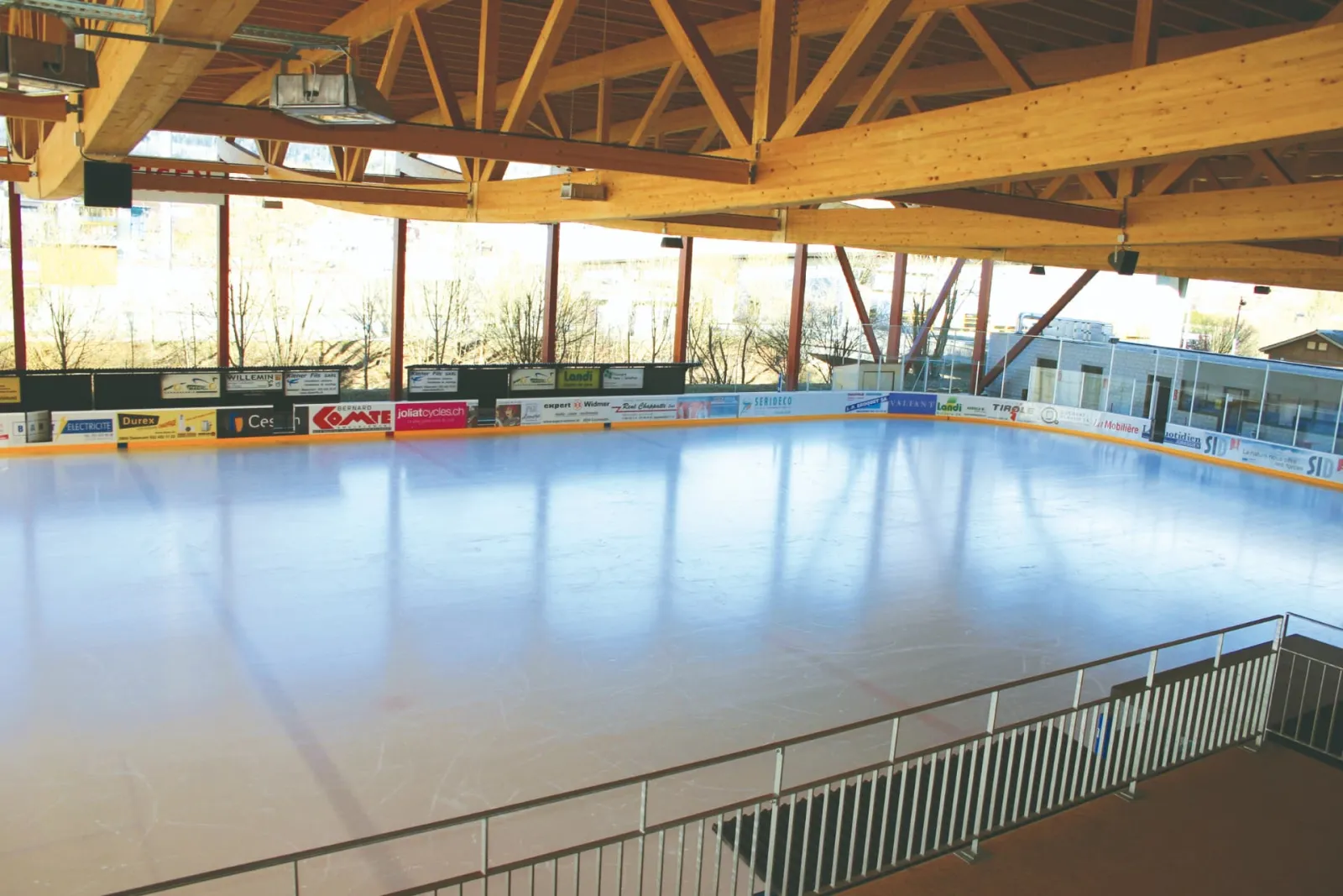 La glace de la patinoire régionale de Delémont, couverte mais ouverte sur les côtés, sous sa charpente en bois — Patinoire régionale de Delémont