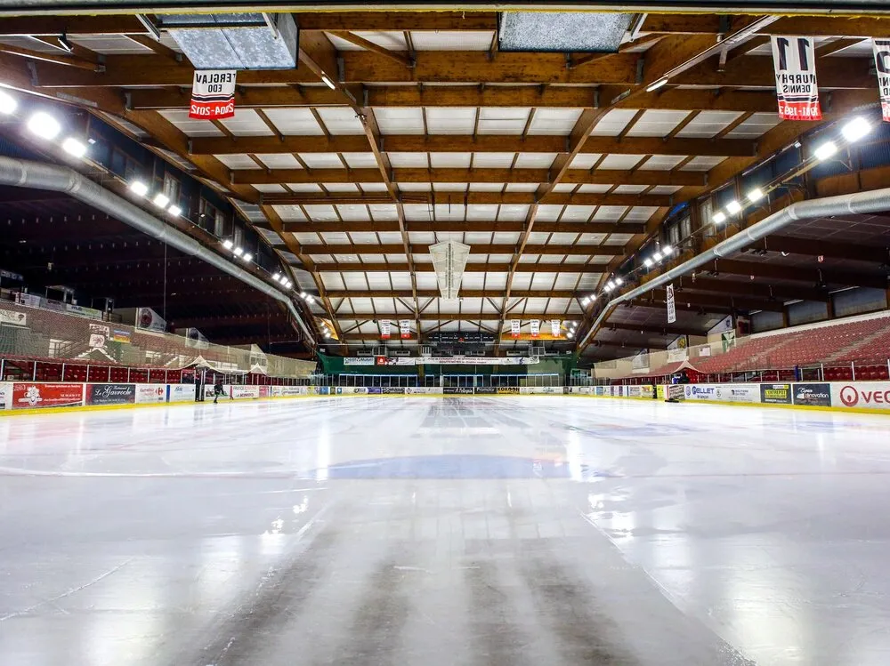La glace vide et la charpente en bois de la patinoire René Froger à Briançon, vues depuis une extrémité. — Patinoire René Froger