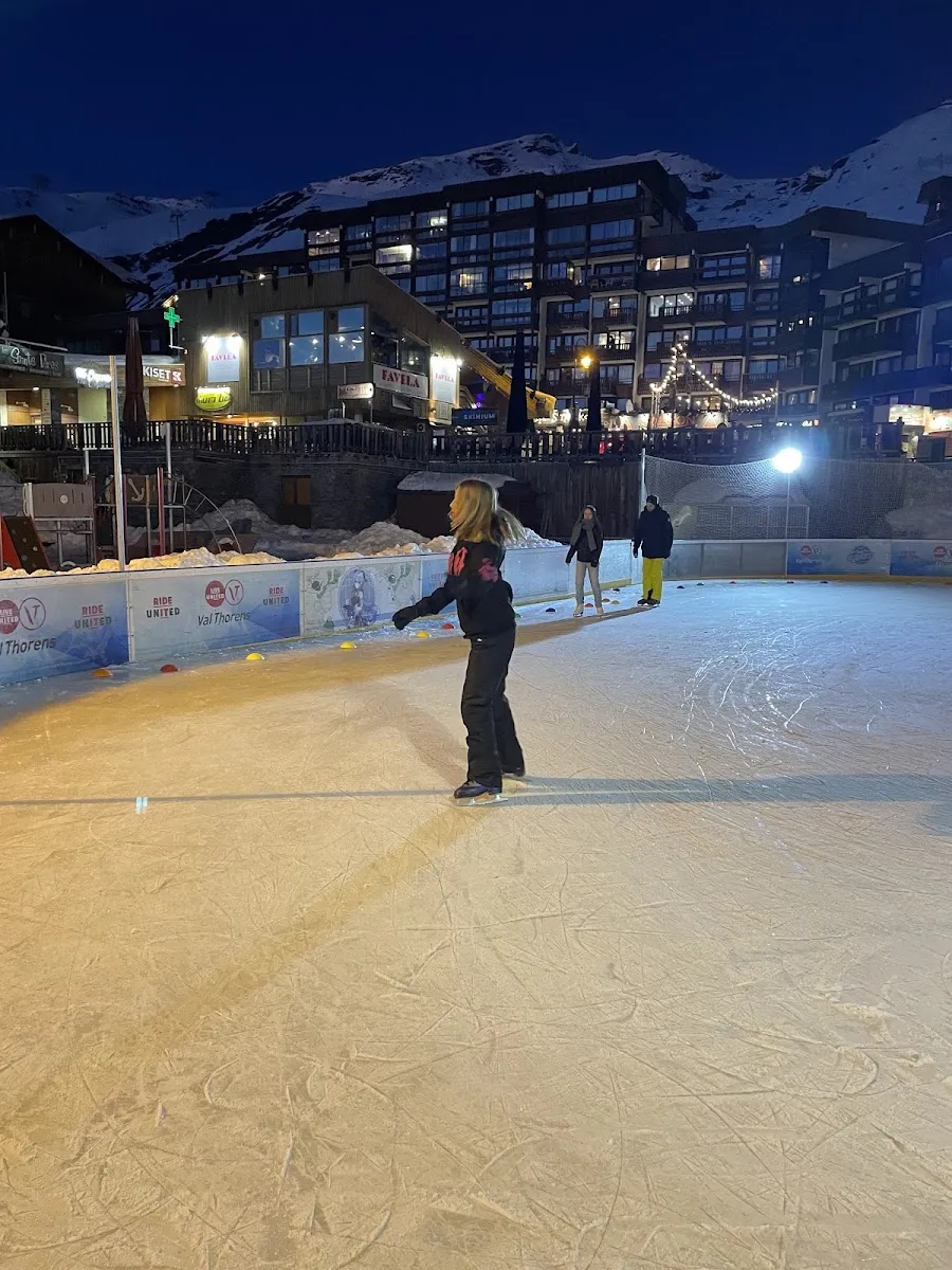 Une patineuse sur la glace naturelle de la patinoire de Val Thorens en soirée — Patinoire de Val Thorens