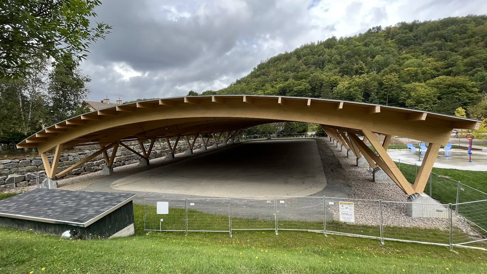 The timber-roofed covered rink at Parc Daniel-Lauzon, Mont-Tremblant, seen from the park — Patinoires du parc Daniel-Lauzon