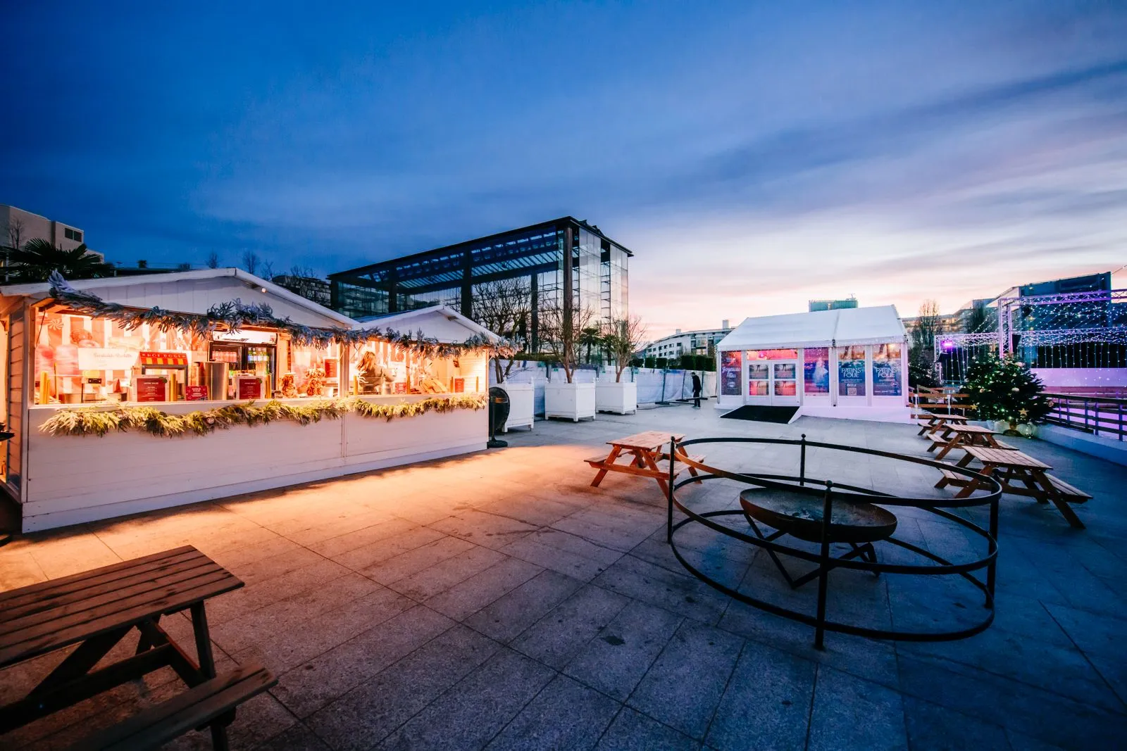 The Patins en Folie chalets and the white event tent at dusk beside the rink in Parc André-Citroën — Patins en Folie au Parc André-Citroën