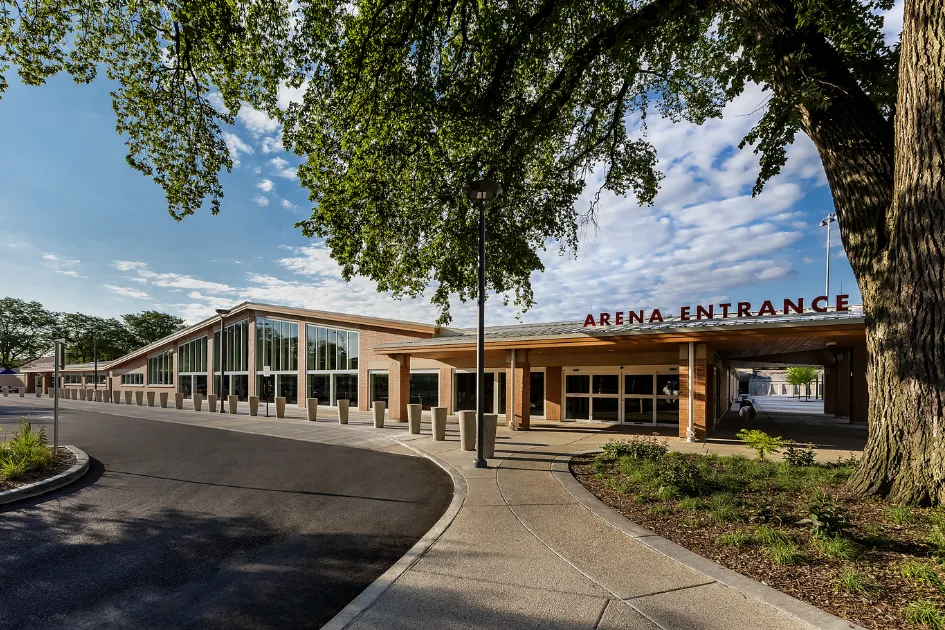 The Ridgeland Common building from the drive: a long, low brick and glass front with a canopy signed "Arena Entrance", under a large tree. — Paul Hruby Ice Arena