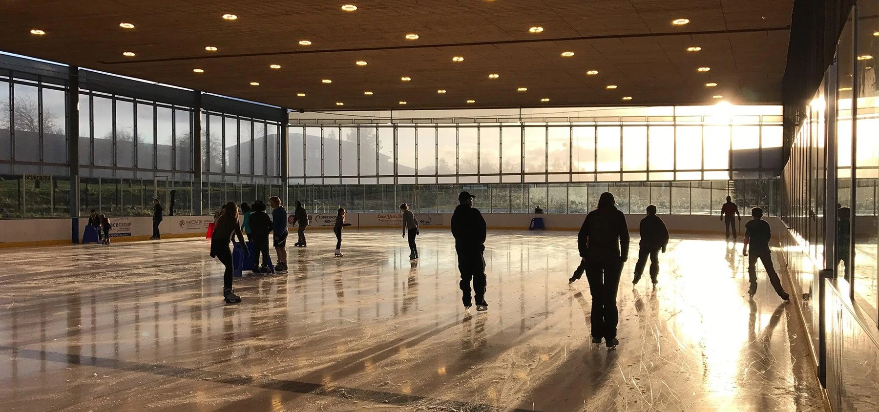 Patinaje sobre hielo bajo el techo de madera de The Pavilion con luz del atardecer. — The Pavilion
