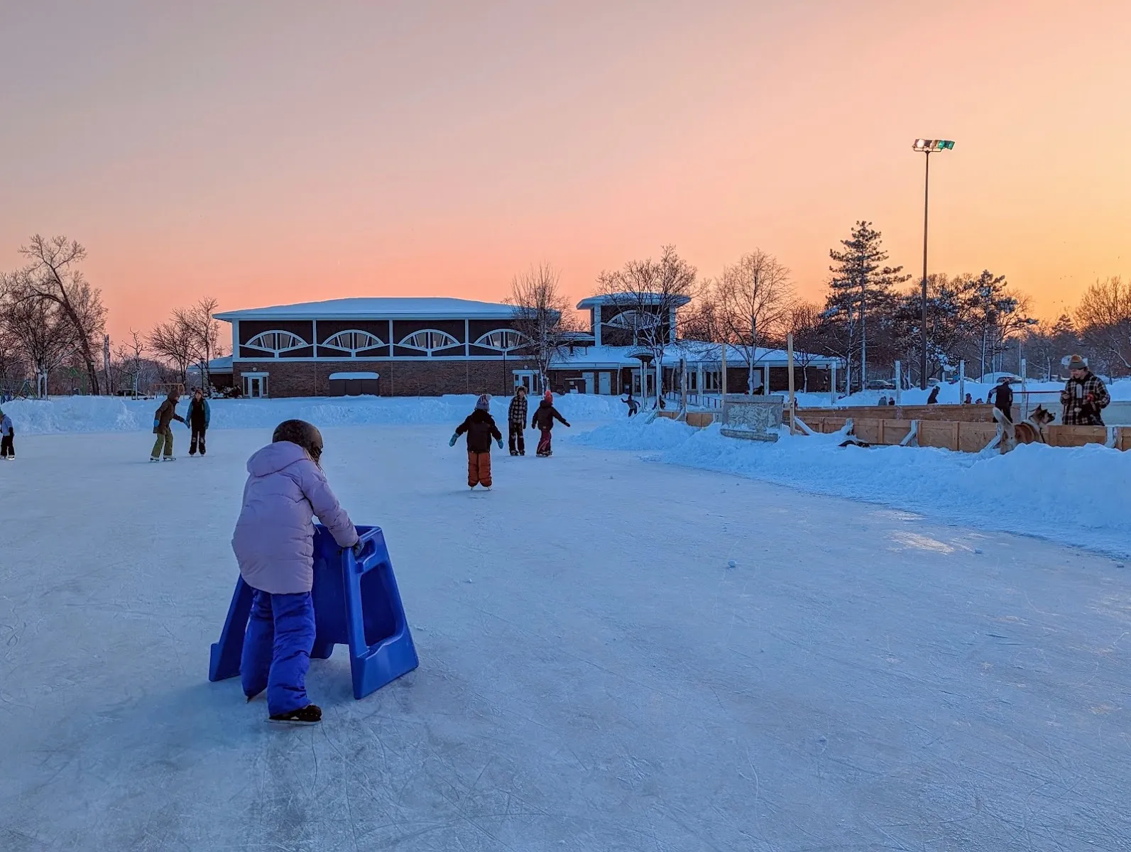 Skater on the ice at Pearl Park, Minneapolis, at dusk with the recreation center behind (Google Maps listing photo) — Pearl Park Outdoor Rink