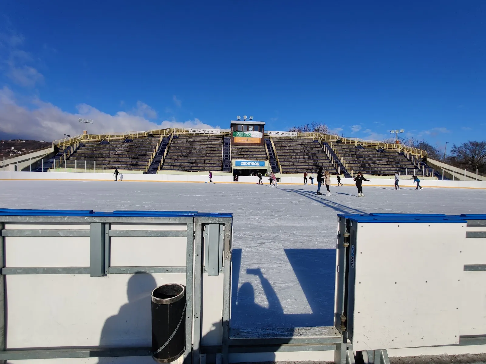 The Pécs Városi Műjégpálya seen across the boards, with the stand and the ticket hut on the far side — Pécs Városi Műjégpálya