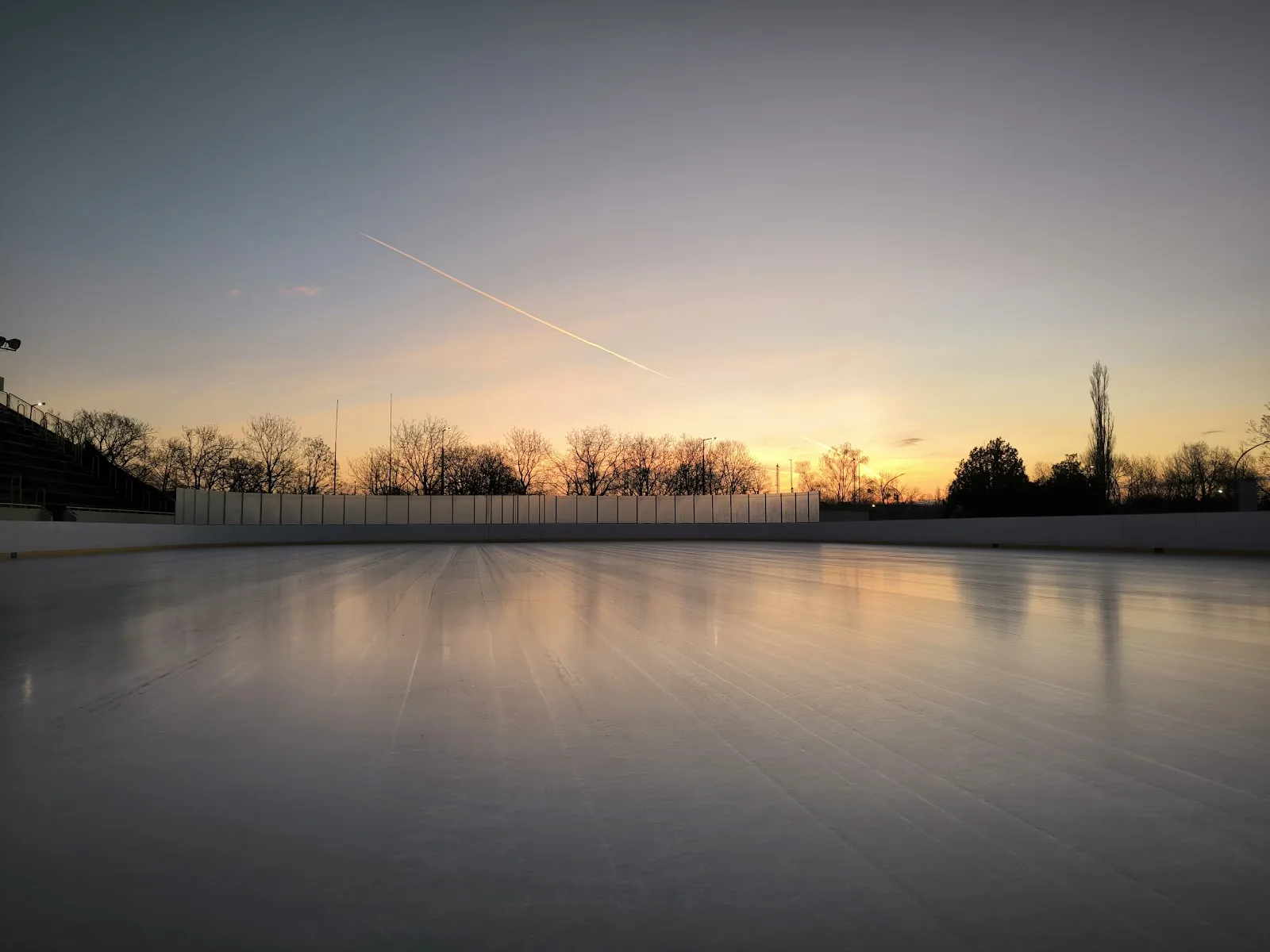 The empty outdoor ice sheet of the Pécs Városi Műjégpálya at sunset — Pécs Városi Műjégpálya