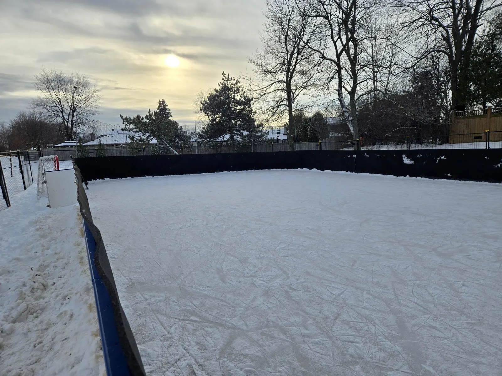 La superficie de hielo con vallas de la pista al aire libre de Peel Village Park bajo un cielo de invierno — Peel Village Park Outdoor Skating Rink