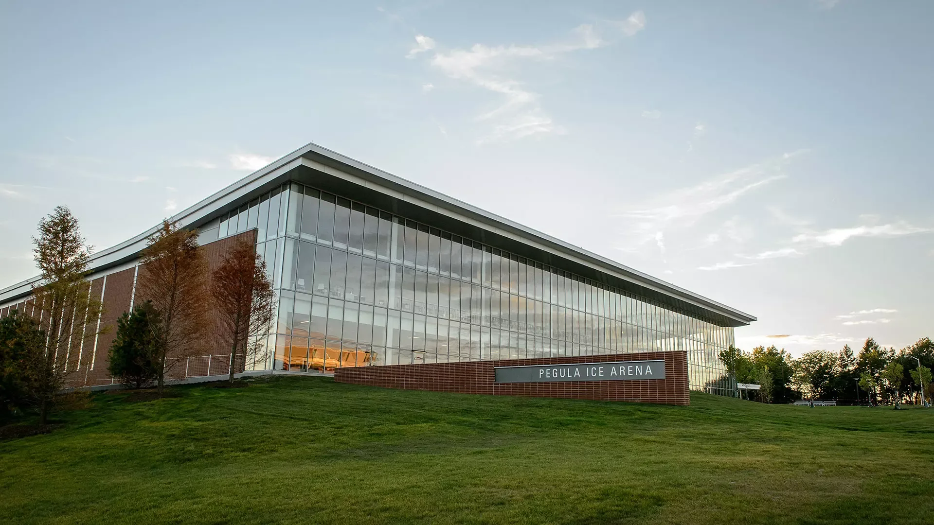 Pegula Ice Arena en la hora dorada, vista desde abajo de una extensión de pasto — Pegula Ice Arena (Penn State)