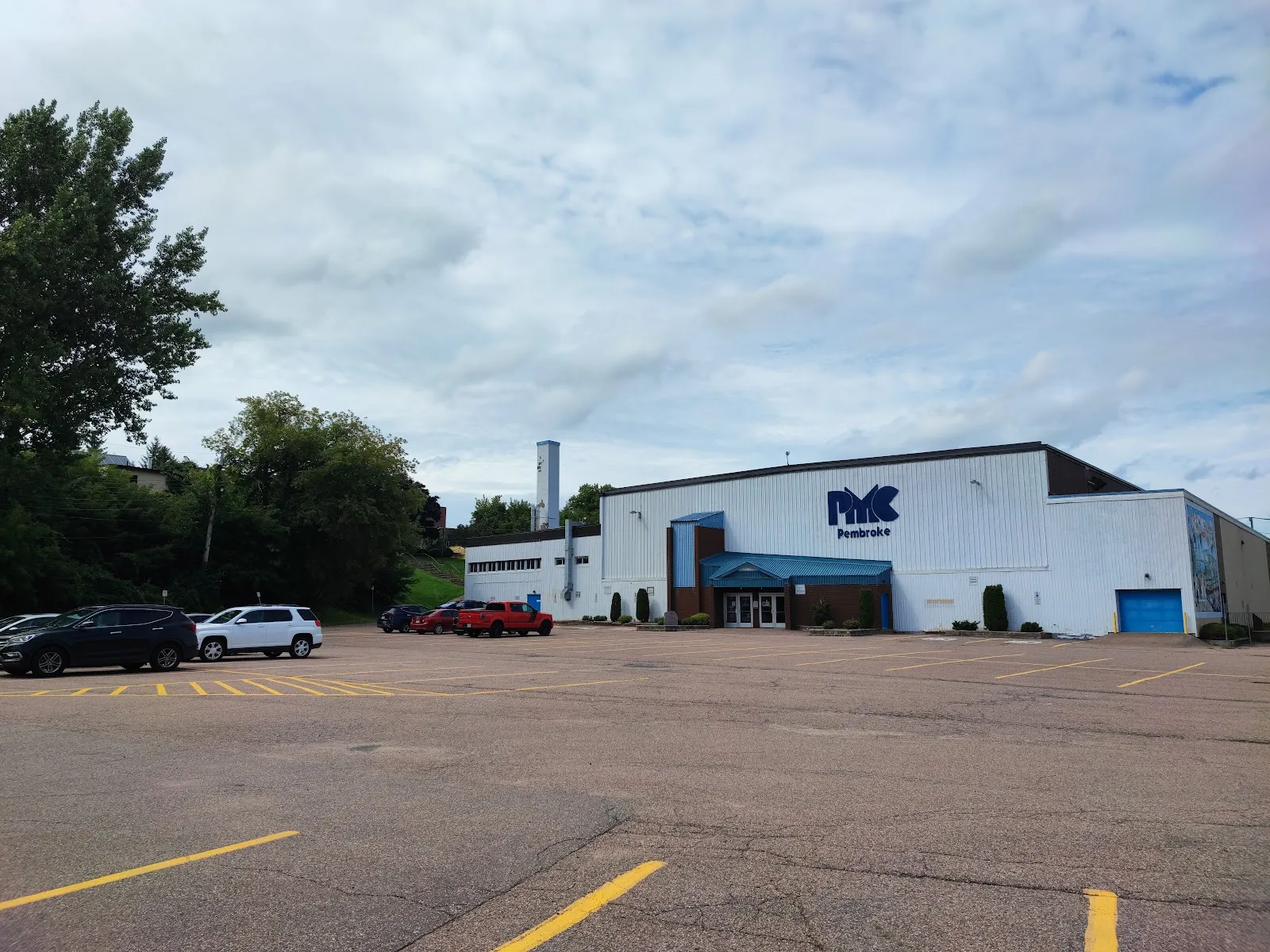 The Pembroke Memorial Centre seen across its car park, a white and blue arena building with the PMC sign above the entrance. — Pembroke Memorial Centre