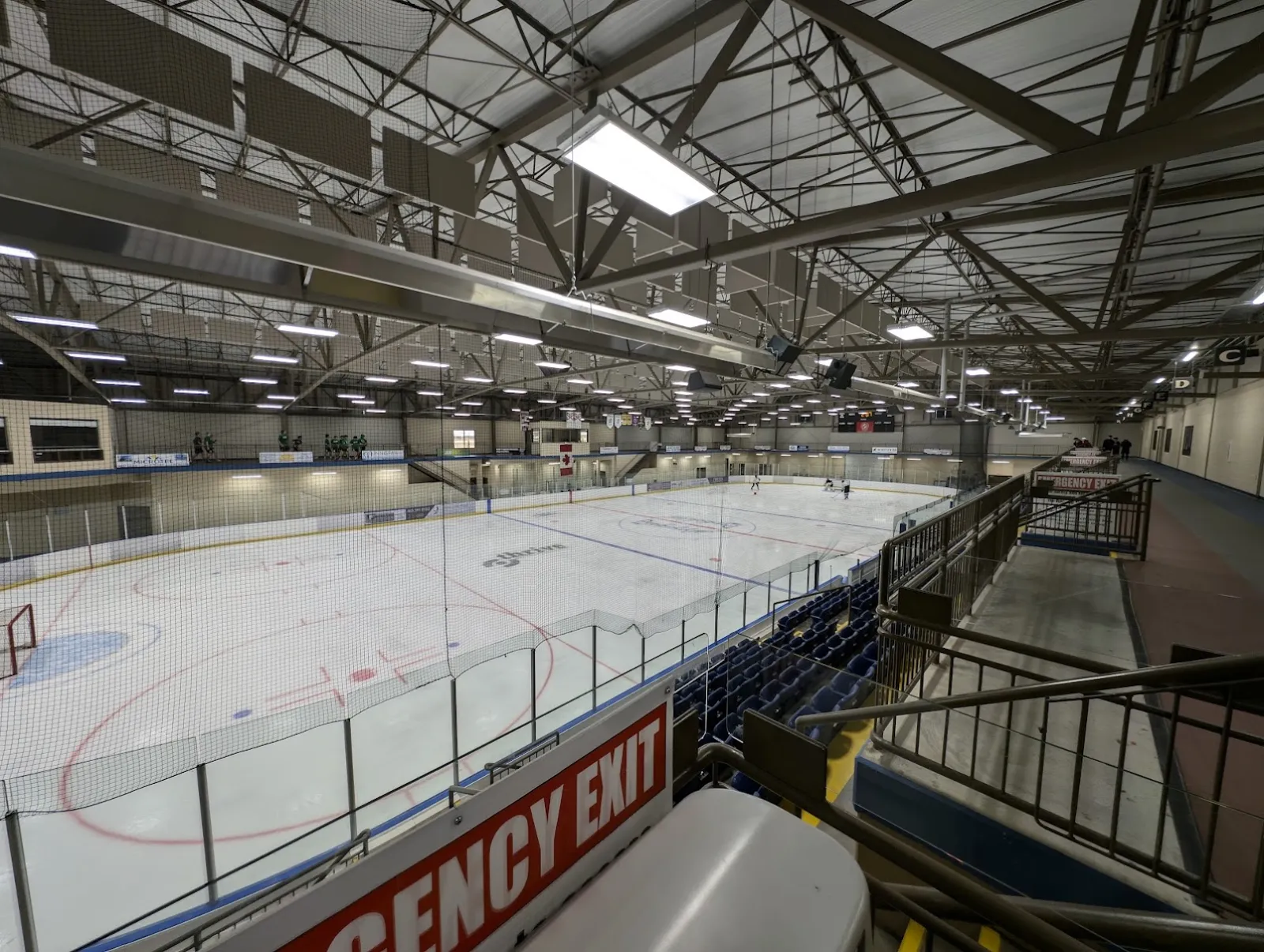 The NHL-size sheet at the Penhold Regional Multiplex seen from the upper level, with the stands and fitness track along the near side. — Penhold Regional Multiplex