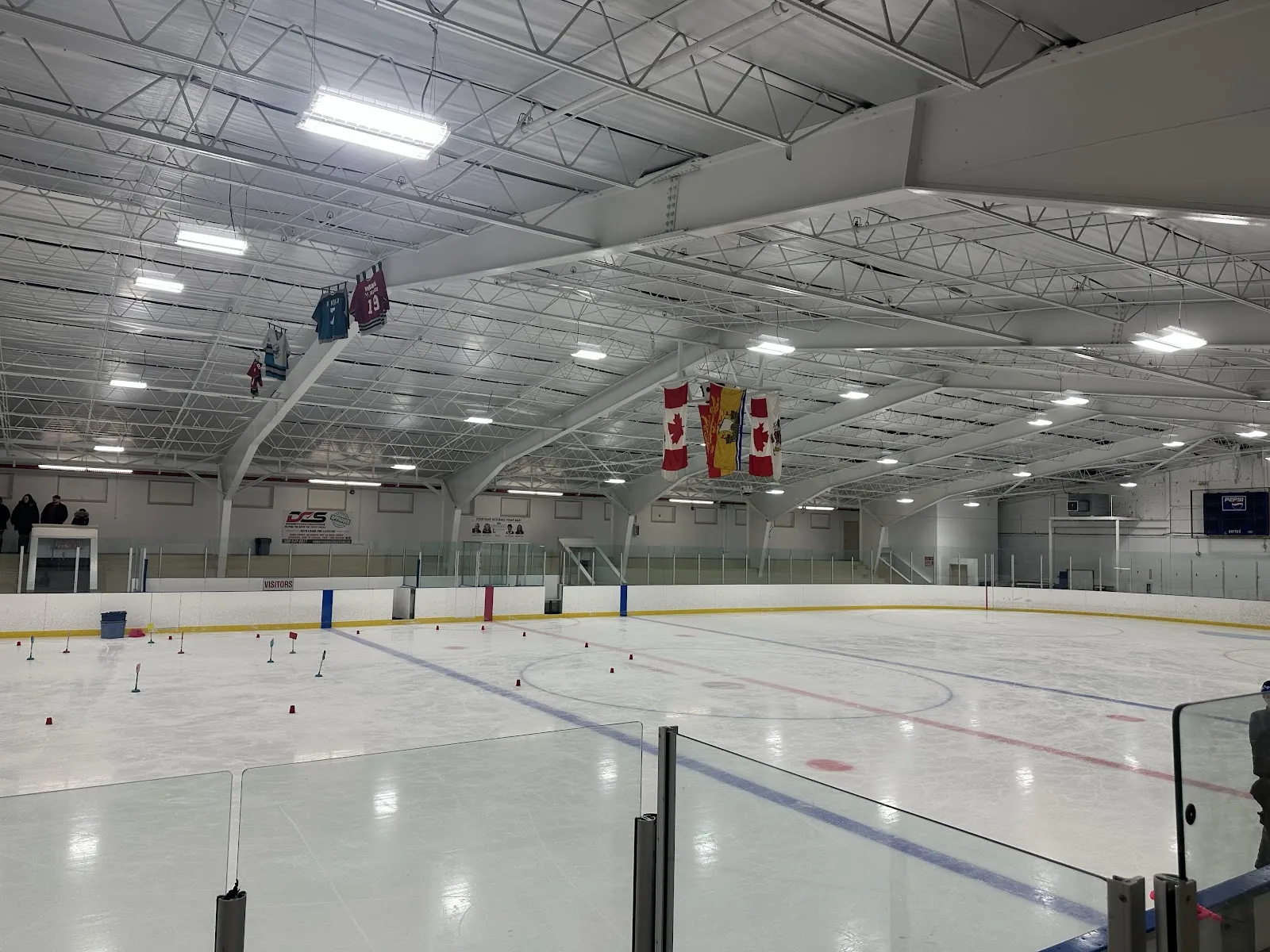El hielo de la Peter Murray Arena con pucks de práctica dispersos cerca de las bardas, y banderas canadienses y mantas colgando del techo. — Peter Murray Arena