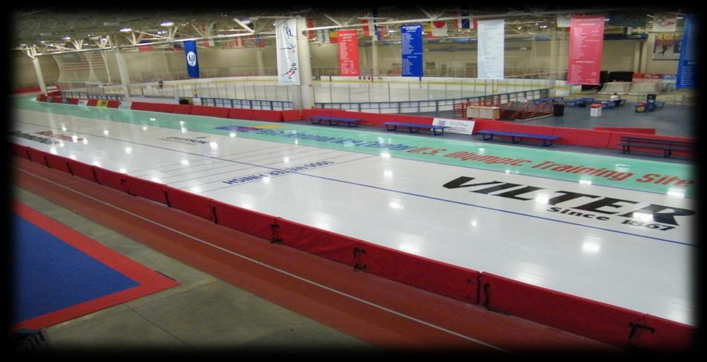 El óvalo de patinaje de velocidad de pista larga, bordeado de protecciones rojas de seguridad, con la leyenda U.S. Olympic Training Site sobre el hielo. — Pettit National Ice Center