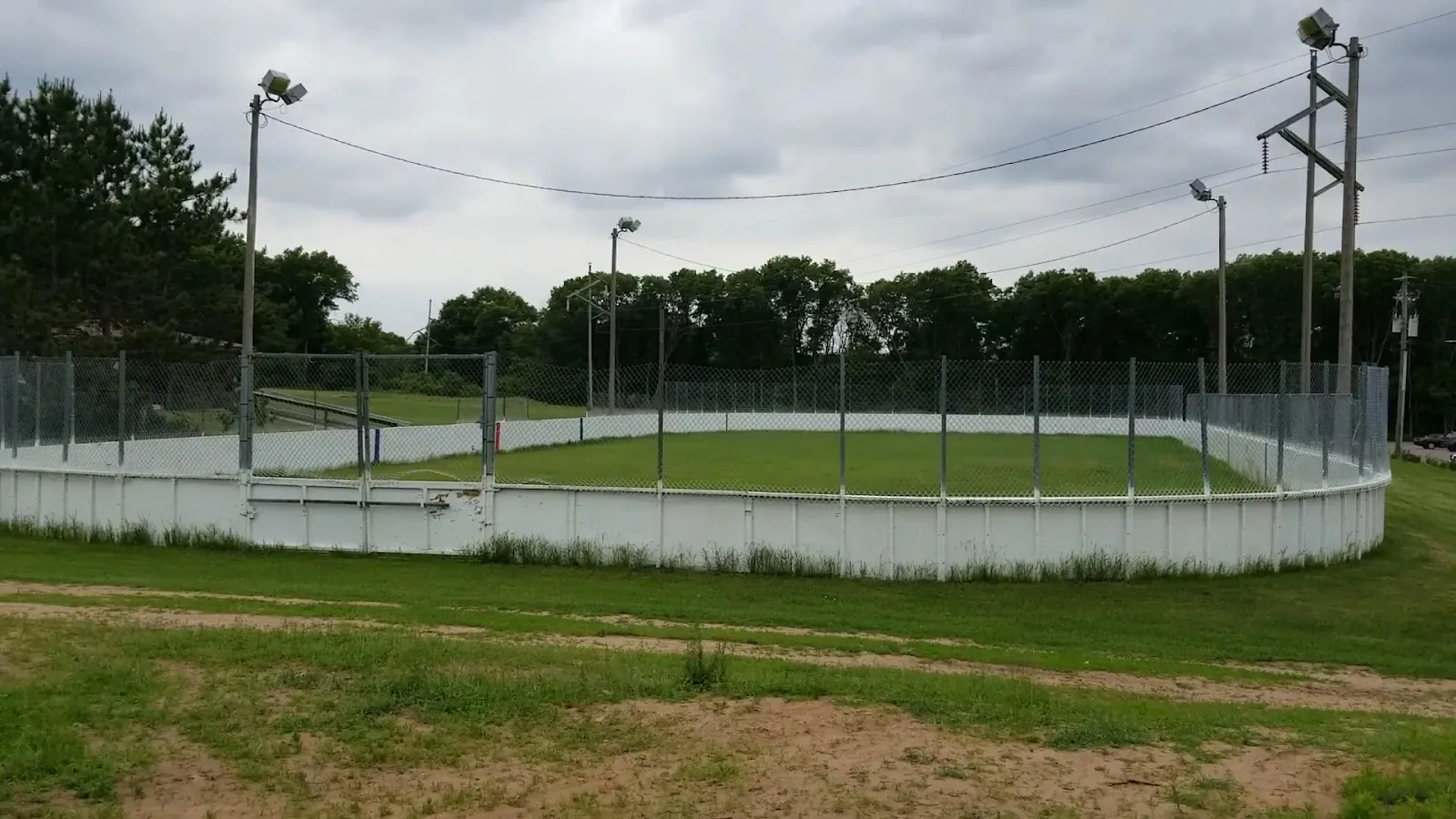 The boarded hockey rink at Pinehurst Park, Eau Claire, with its rink lights, in summer (Google Maps listing photo) — Pinehurst Park Outdoor Rinks
