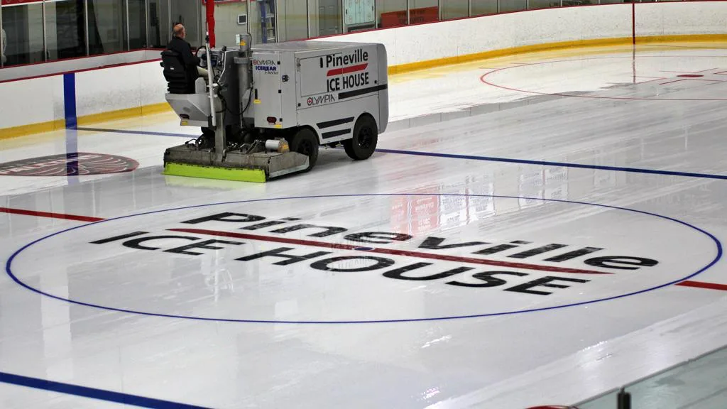 Pulidora de hielo Olympia en plena inundación junto al logotipo de Pineville Ice House en el centro de la pista — Pineville Ice House