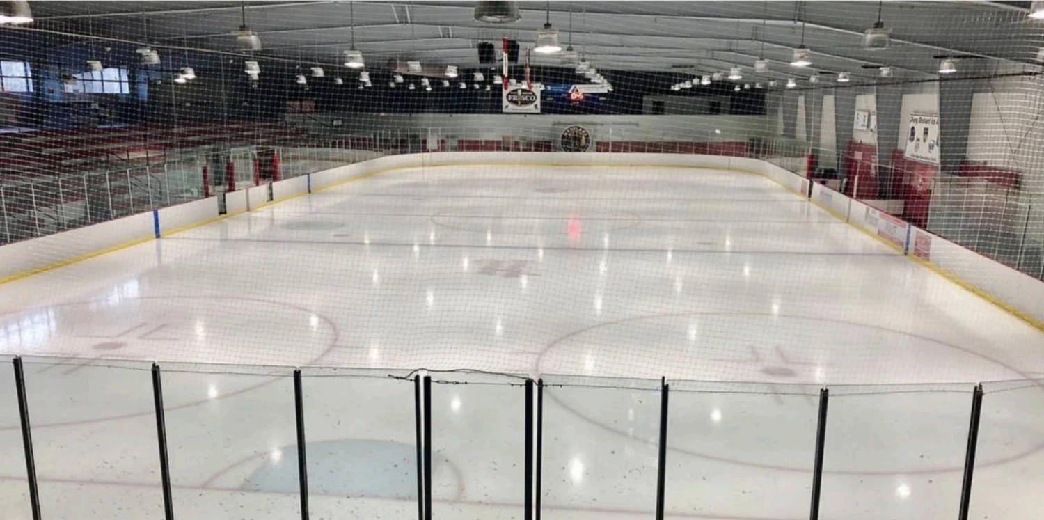 Una amplia vista a lo ancho del hielo de Piney Orchard, con detalles rojos en la pista y asientos para espectadores a un lado. — Piney Orchard Ice Arena