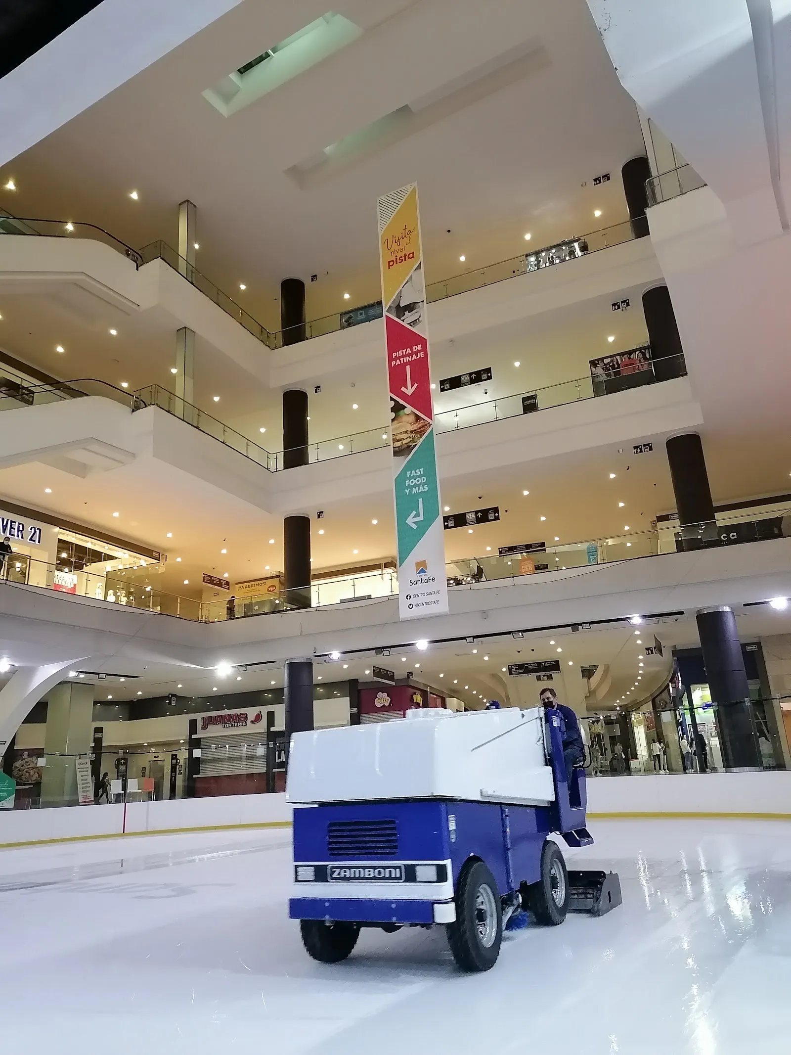 The resurfacer on fresh ice at the Santa Fe mall rink, with the multi-storey atrium and its walkways rising behind the boards — Pista de Hielo Centro Santa Fe