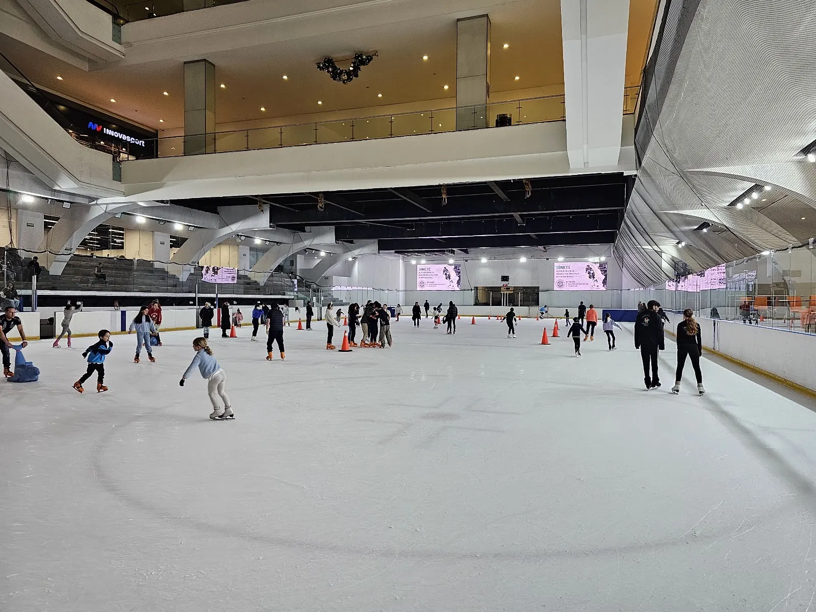 The Centro Santa Fe rink during a public session, under the mall atrium with the stands at the far end — Pista de Hielo Centro Santa Fe