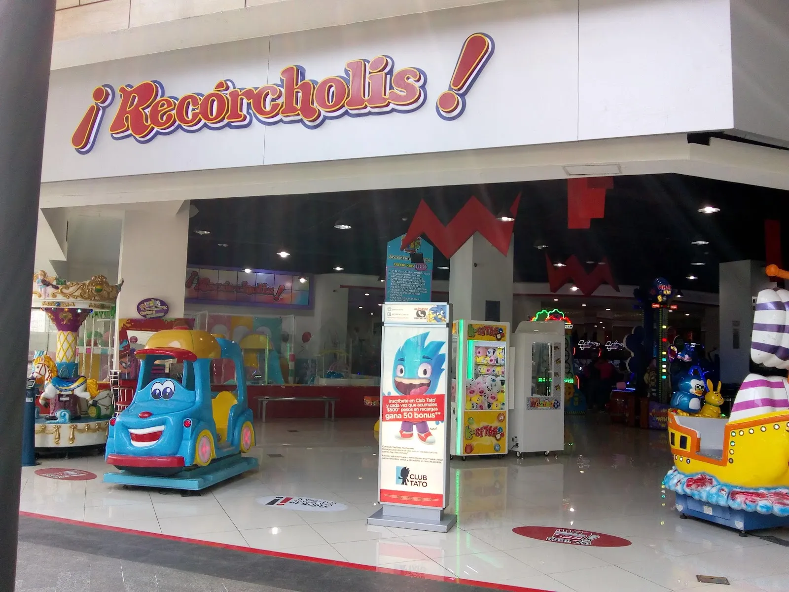 La entrada del centro de entretenimiento ¡Recórcholis! en el centro comercial Vía Vallejo, con su letrero rojo sobre los juegos infantiles de monta junto a la entrada. — Pista de Hielo ¡Recórcholis! Parque Vía Vallejo