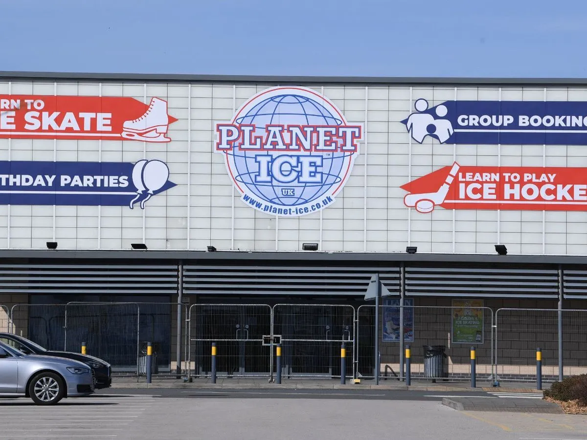 The pale cladded front wall of the arena with the Planet Ice globe, 'Learn to skate', 'Birthday parties', 'Group booking' and 'Learn to play ice hockey' signs above the entrance fencing. — Planet Ice Widnes