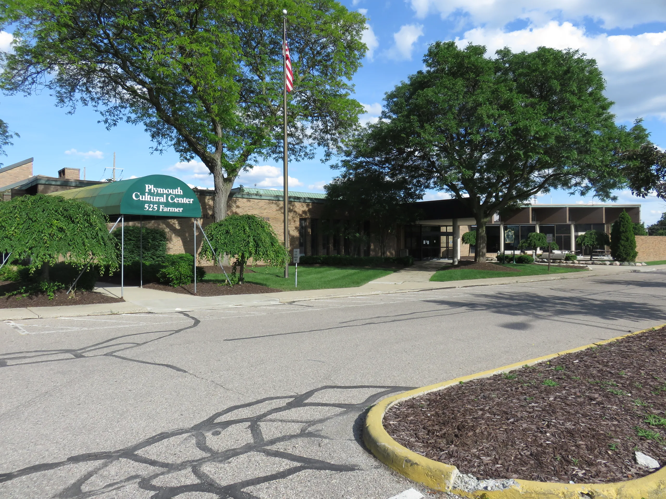 Green awning and flagpole across the empty parking lot — Plymouth Cultural Center Ice Arena