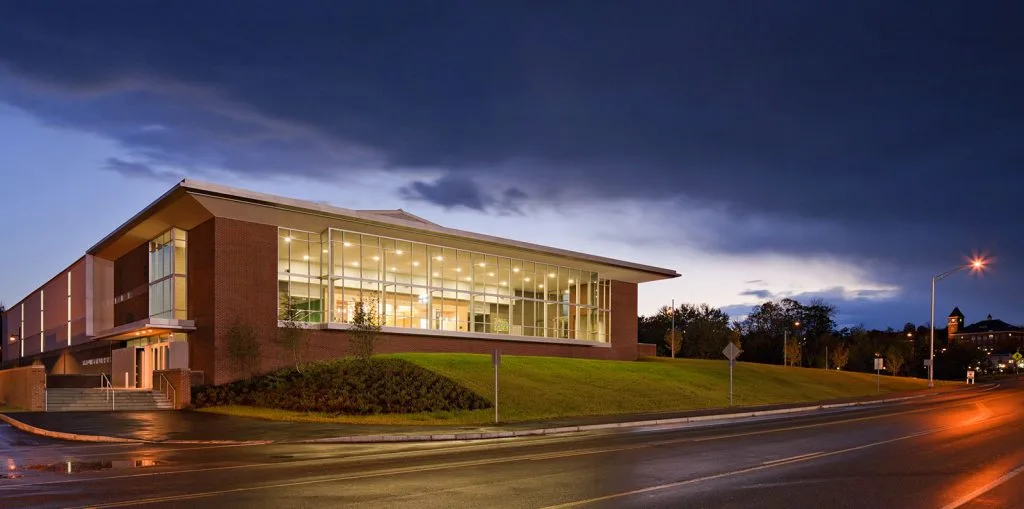 El Plymouth State University Ice Arena y el Welcome Center al anochecer, vistos desde Holderness Road. — Plymouth State University Ice Arena