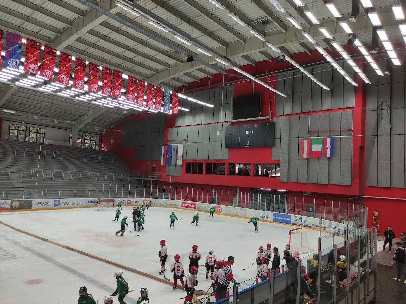 Youth hockey on the ice at the Podmežakla hall seen from the stands, players at a distance — Podmežakla Sports Hall